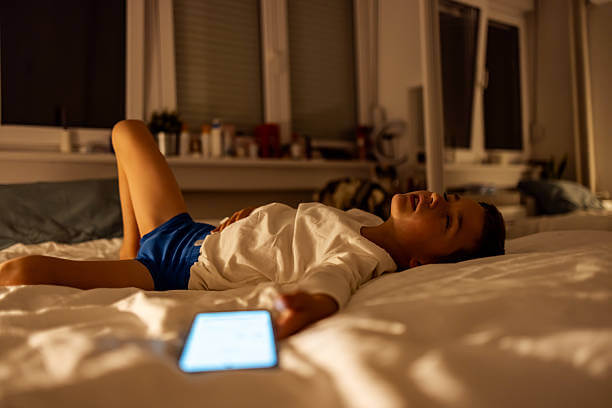 휴대전화를 쥔채로 침대에 잠이 든 아이