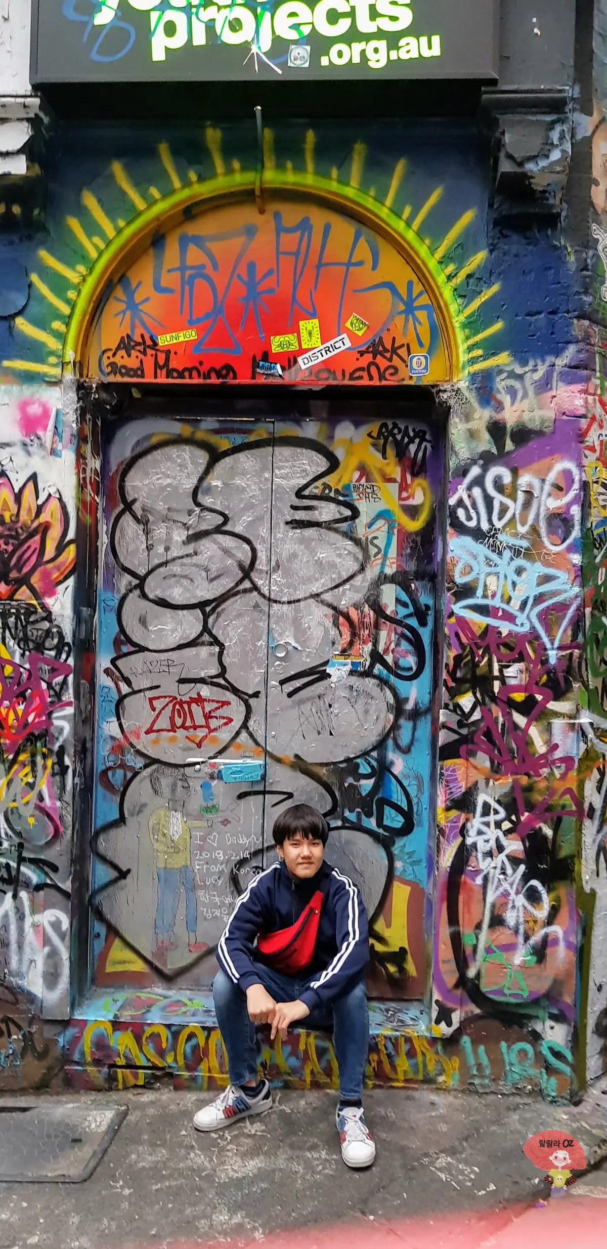 호주-멜버른-호시어-레인-거리-알록달록-그래피티-장식-문-앞에-앉아-미소짓는-소년