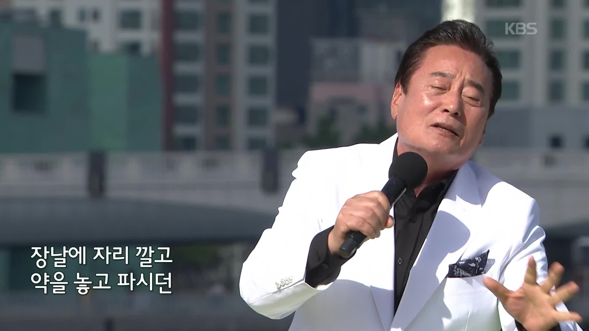 흰 재킷을 입고 마이크를 든 김성환의 방송 장면