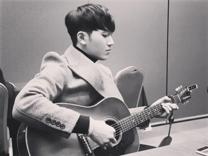 김필이-자켓을-입고-의자에-앉아-기타를-치는-사진