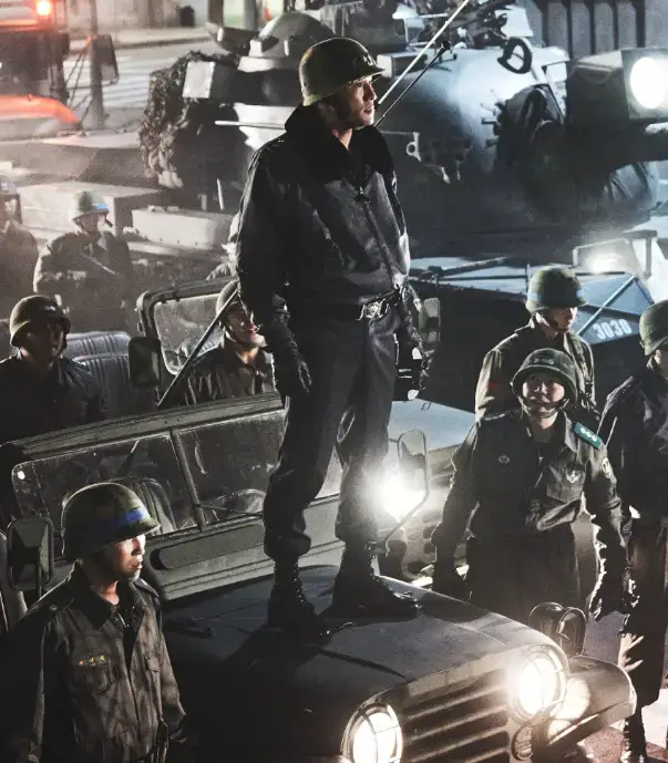 군인 철모를 쓰고 군인잠바와 군인바지 워커화를 신고 군용 지프차에 서있는 전두광