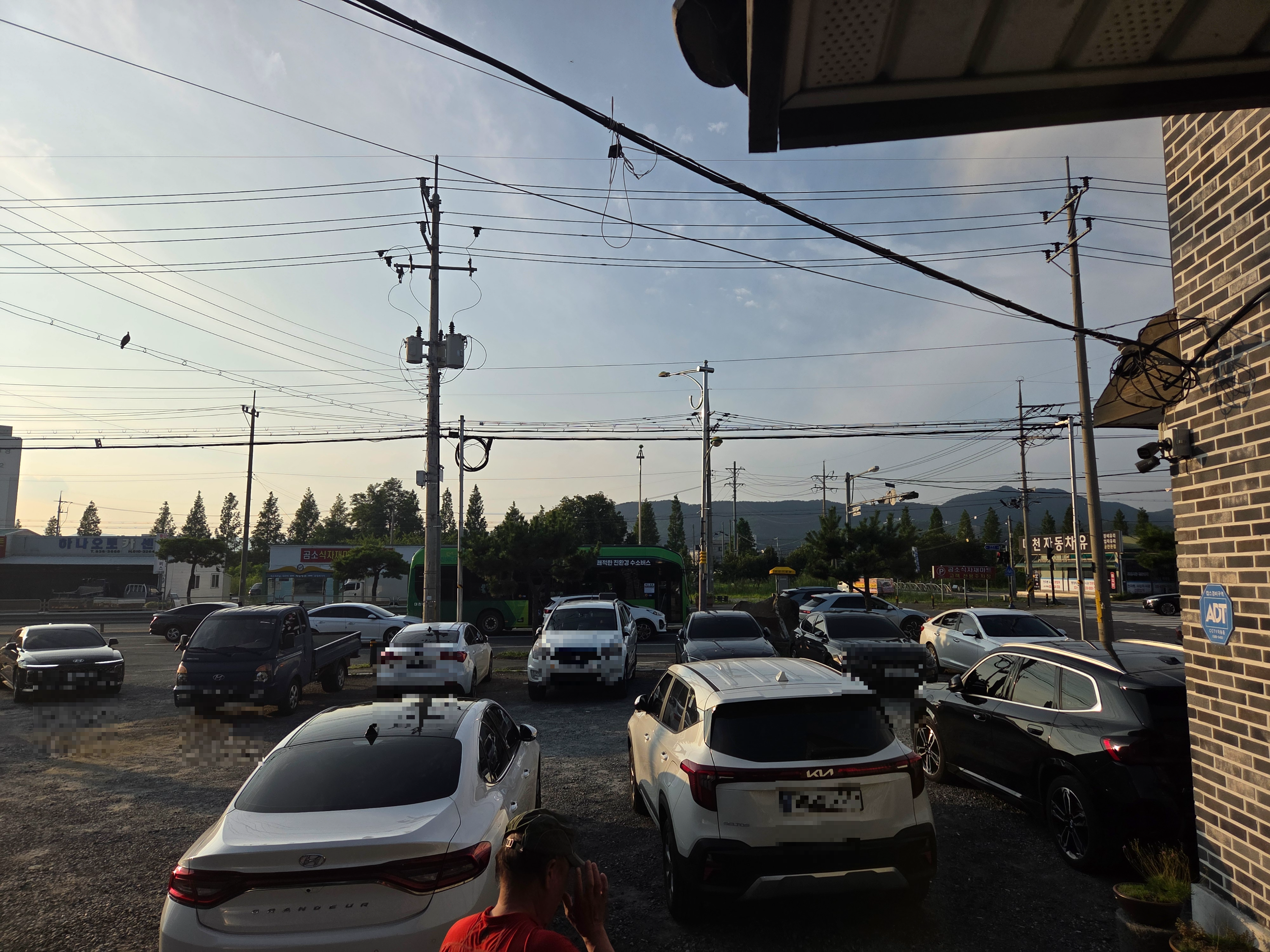 신화정 식당 옆 넓은 자갈밭 주차장, 차량들로 만차인 모습