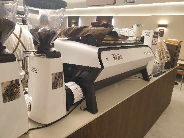 하얀색 그라인더와 하얀색 커피 머신이 놓여있다.