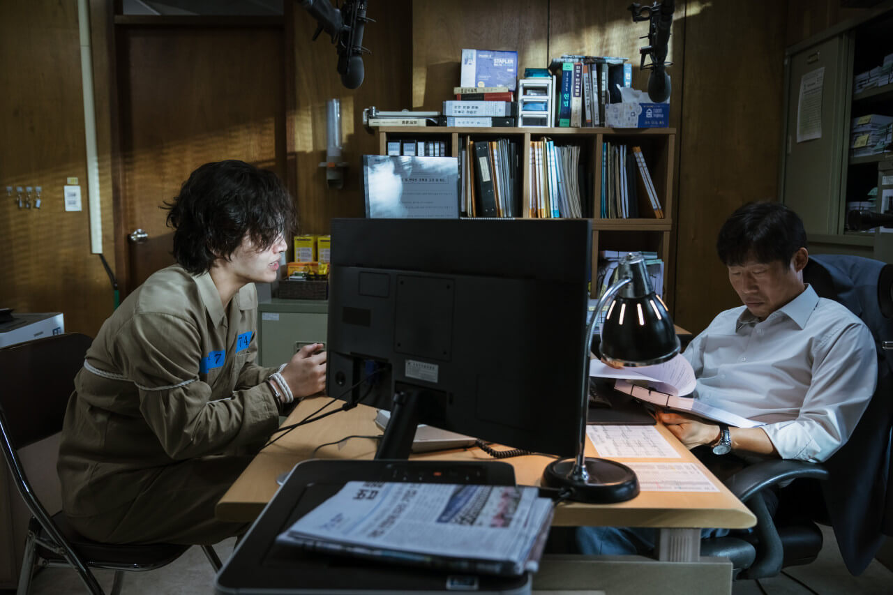 영화 야당 속 주인공 구관희와 이강수가 책상을 사이에 두고 앉아있는 모습