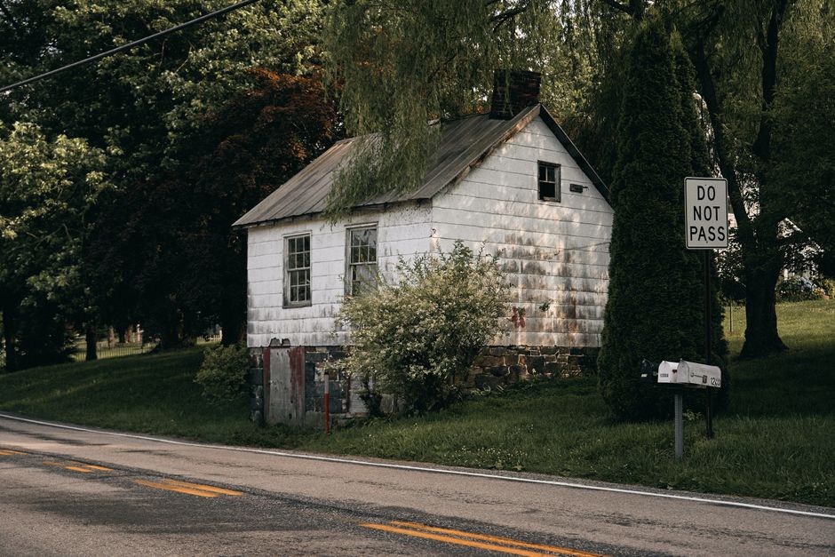 Vintage white house by a serene road with lush greenery in York Haven, PA.