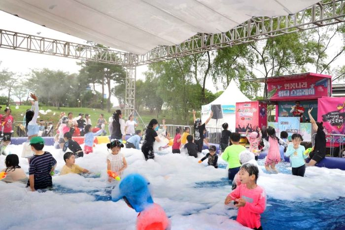 거품놀이 체험존에서 물놀이를 즐기는 아이들과 가족들&amp;#44; 즐거운 축제 분위기