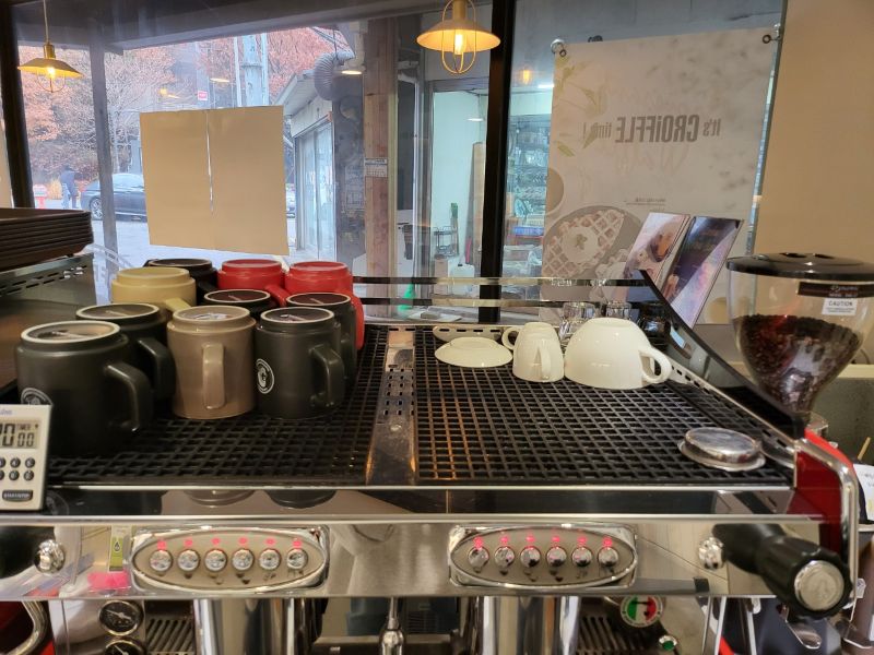 에스프레소 머신 위에 세척 후 정갈하게 정리된 다양한 색상의 머그컵들