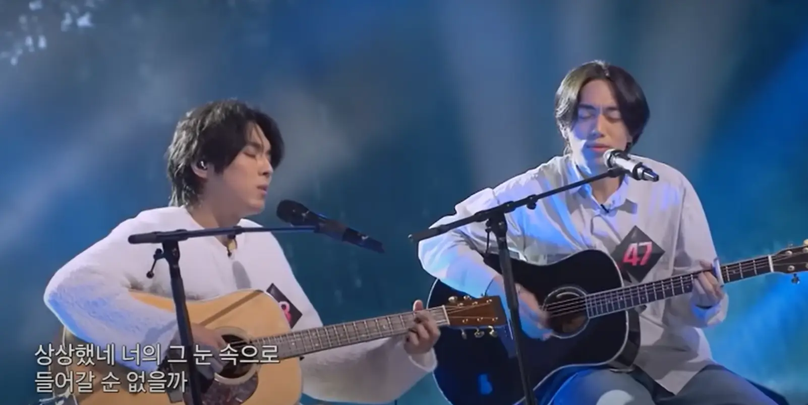 싱어게인3- 우측 베이지색 셔츠와 청바지에 가슴에 47번호표를 달고 검은색 기타를 치며 스탠딩마이크를 앞에 두고 앉아 두눈 감은채 노래하는 47호와 좌측 연노란바지에 흰색 니트를 입고 갈색기타를 치며 스탠딩마이크를 앞에두고 앉아서 노래하는 58호