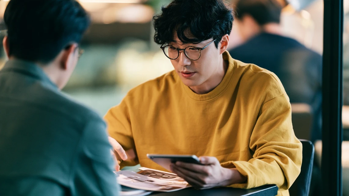 탁자 위 자료를 사이에 두고 대화하는 두 사람
