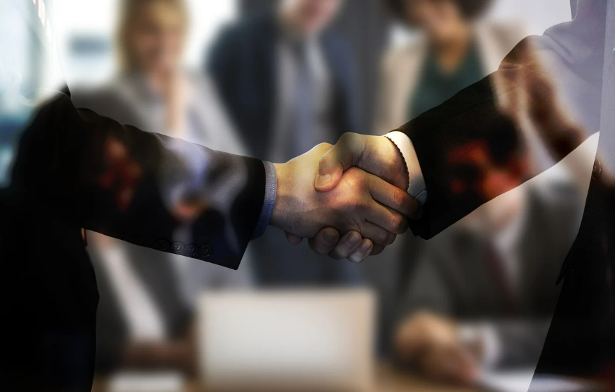 박수치는 사람들 앞에서 악수하는 두 손