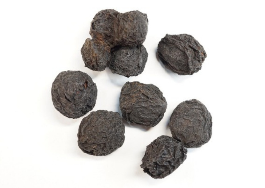 야생에서 채취를 한 청매실을 씨를 빼고 불을 때어 연기에 그을리고 말려서 만든 오매를 하얀 바닥 위에 10개 놓아두고 찍은 사진