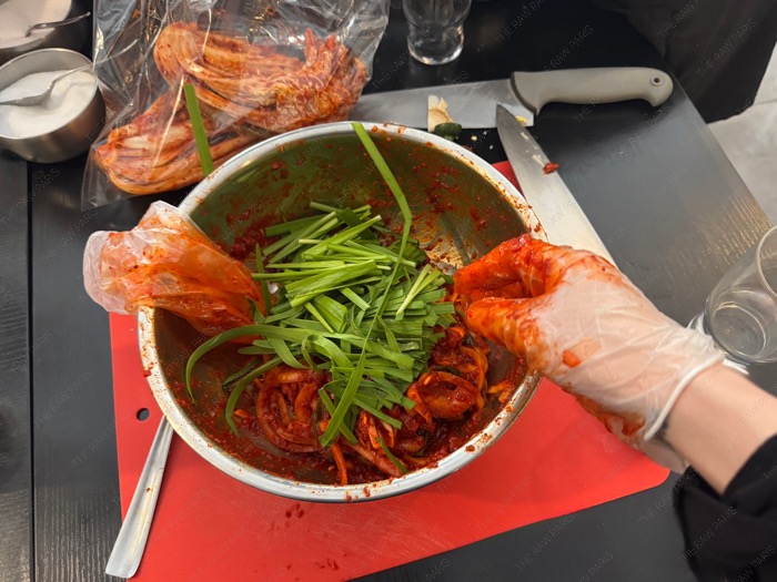 Mixing fresh chives into the red chili paste by hand to make the Kimchi filling ❘ Mélange à la main de ciboule fraîche dans la pâte de piment rouge pour faire la farce du Kimchi