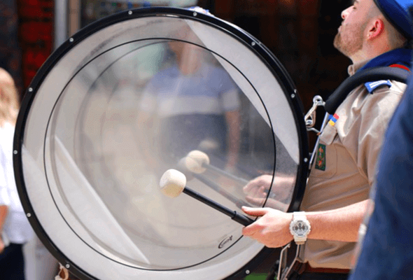 백인 남자가 커다란 북을 지고 두드리면서 거리 행진을 하고 있다.