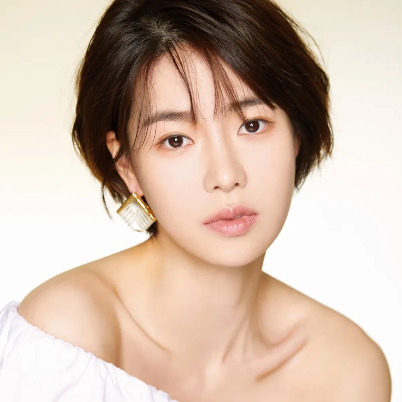흰색을 배경으로 갈색 숏컷에 어깨가 드러난 흰 드레스를 입고 있는 배우 임지연