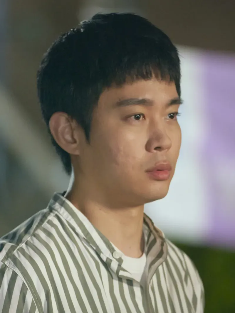 카키색 스트라이프 패턴의 와이셔츠를 입고 서 있는 드라마 낮에 뜨는 달의 정윤제 캐릭터