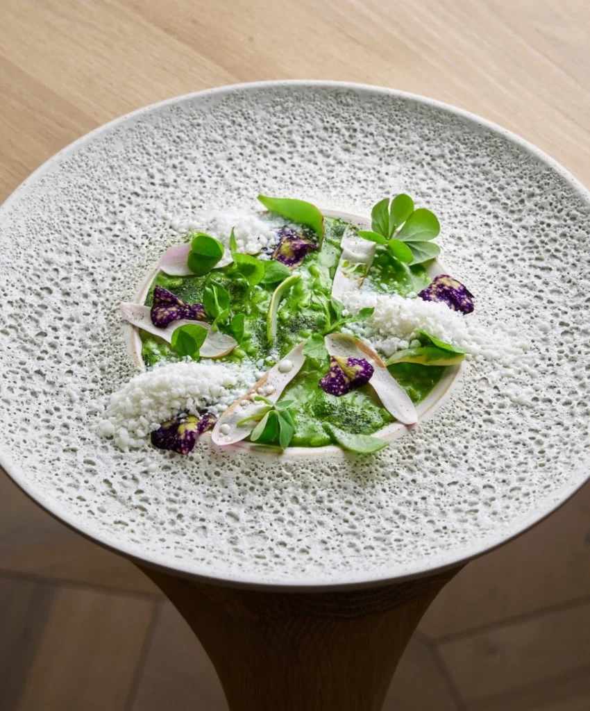 Artistically plated green sauce dish with edible flowers and microgreens at Horto, Milan