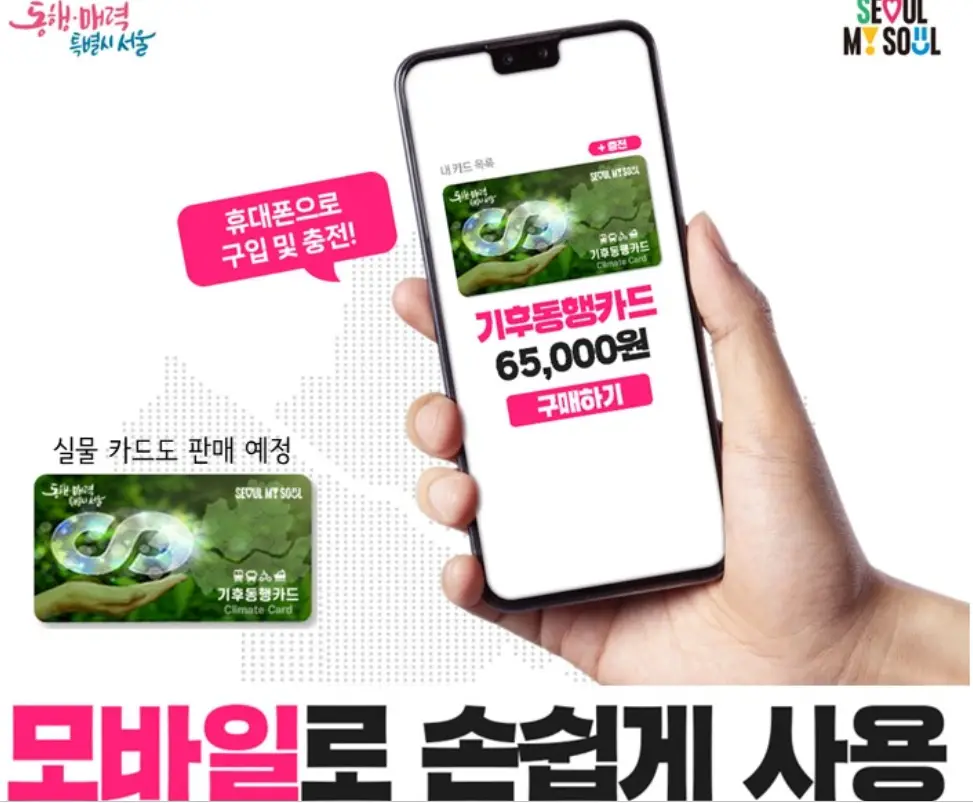 기후동행카드-
오른손으로 핸드폰을 든이미지&#44; 핸드폰안 초록색 실사카드이미지 아래 분홍색 글씨로 기후동행카드 글자 아래 검은색글씨로 65&#44;000원 글 아래 분홍색 사각형안 흰글씨로 구매하기
