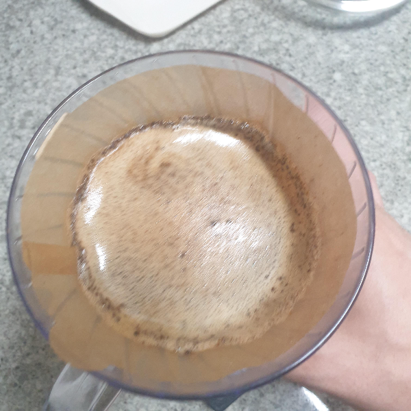 커피에 물을 붓고 손으로 흔드는 모습.