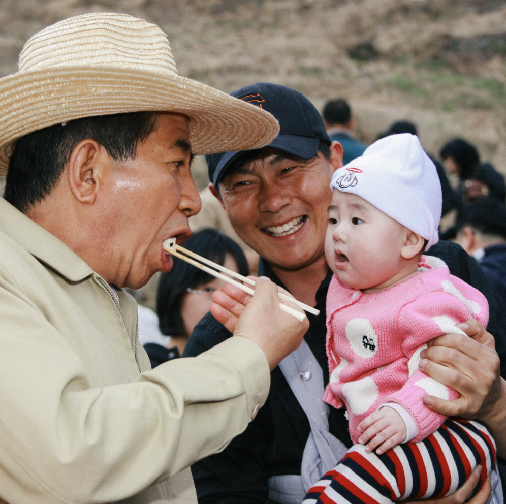 고 노무현 대통령이 아기에게 재미있는 장난을 치는 사진입니다.