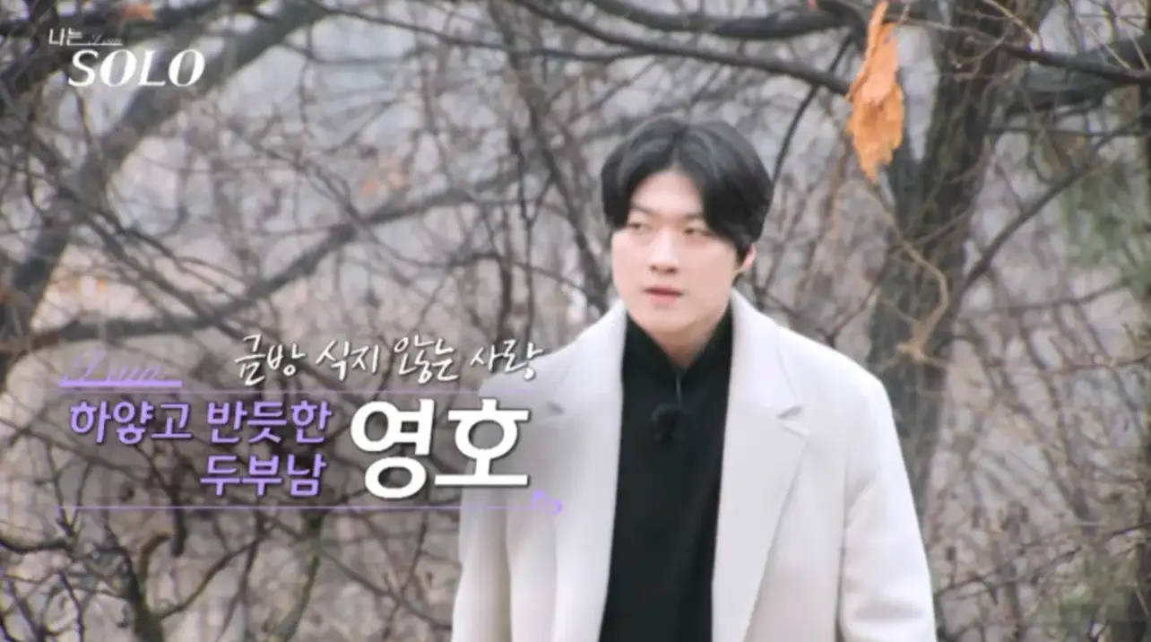 나뭇가지를 뒤로하고 흰색 코트 안 검은 셔츠를 입고 비장하게 걸오은 영호 좌측 보라색 글씨 하얗고 받읏한 두부남 영호