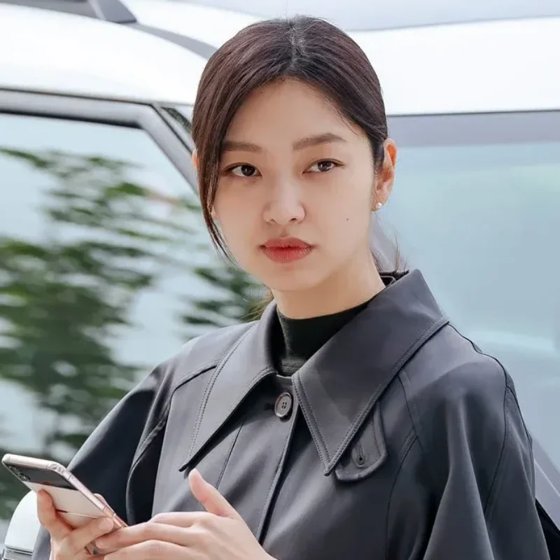 자동차를 배경으로 갈색 긴머리에 검은 정장을 입고 있는 국민사형투표의 채도희