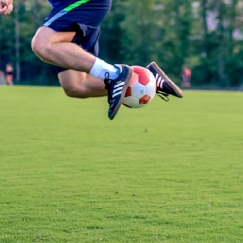 볼을 잡고 점프하는 기술을 보여주는 잔디위 축구선수 모습