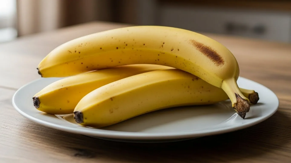 부엌 식탁 위 접시에 잘 익은 바나나 3개가 놓여져 있음