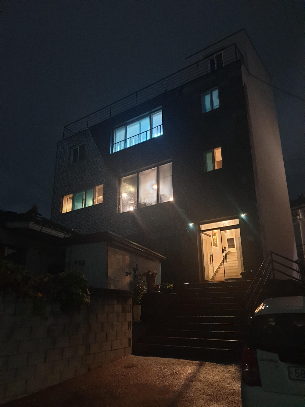 컴컴한 밤 3층 건물에 불이 켜있다. 1층과 2층은 웜조명이다.