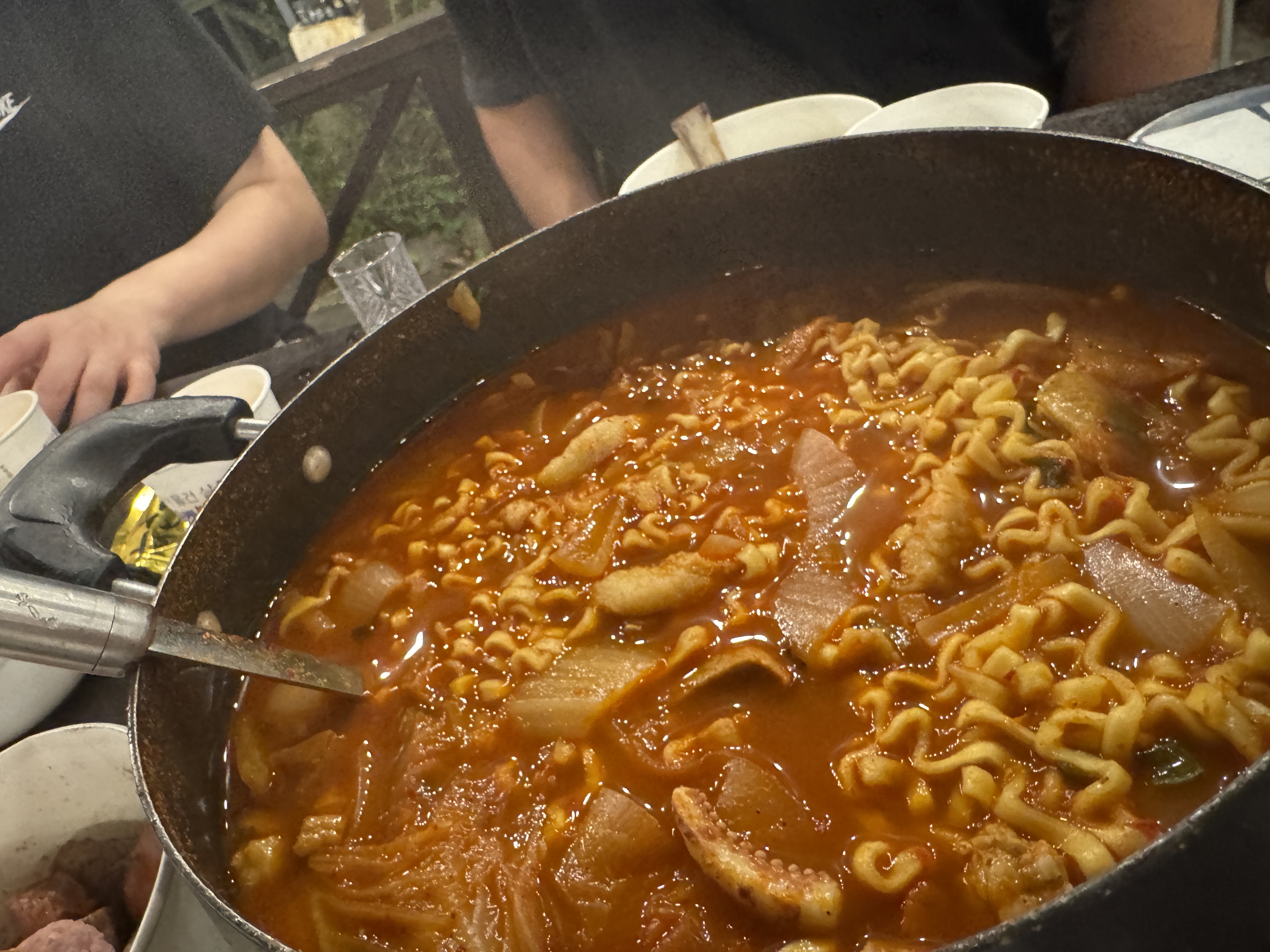 커다란 냄비에 끓고 있는 오징어 김치찌개. 라면사리까지 들어가 국물이 얼큰하고 진하게 우러난다.