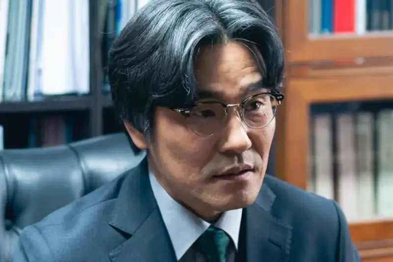 어느 사무실 서류 책장을 배경으로 양복을 입고 머리가 하얀 김치원