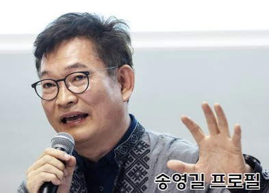 송영길 국회의원 사진으로 정장을 입고 안경을 끼고 마이크를 들고 있음