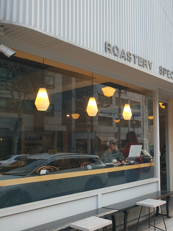 흰색 파사드와 벤치가 있는 외부, 웜 조명이 있는 내부