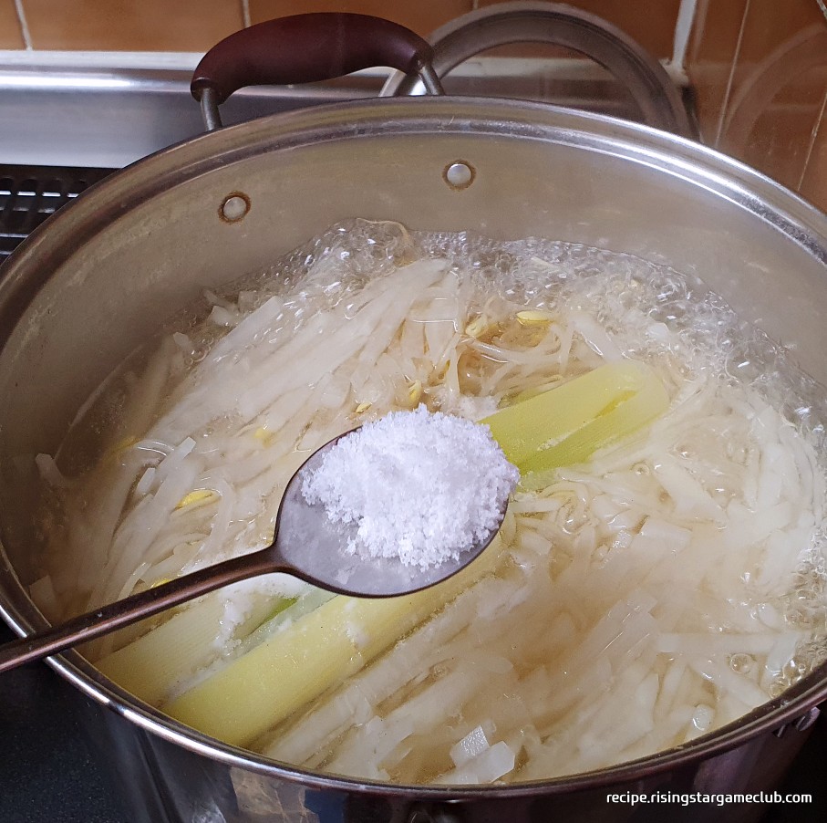 끓고 있는 명절 나물국에 소금을 넣는 사진