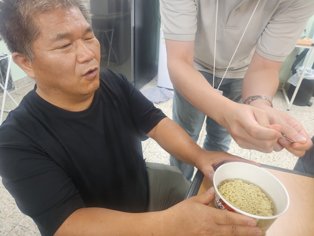 이미지설명: 시각장애인 쉼터 이용인이 물을 붓고 용기를 만져보고 있음.