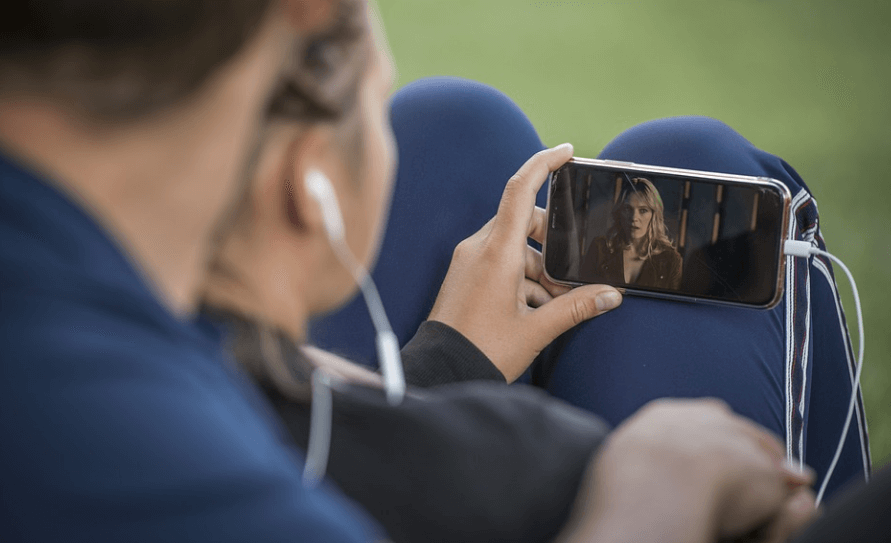 연인이 이어폰을 귀에 꼽고 영화를 보고 있다