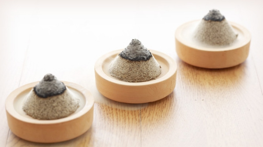 마룻바닥 위에 쑥으로 만든 뜸봉 3개를 나무로 만든 받침대 위에 각각 두고 불을 붙여서 뜸을 뜨는 것을 시연하고 있는 것을 찍은 사진