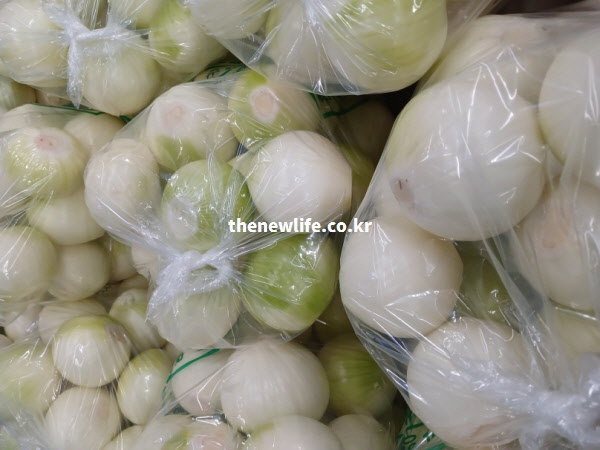 껍질을 깨끗하게 벗겨 비닐에 포장된 신선한 깐 양파들이 가득 담겨 있는 고화질 실물 사진