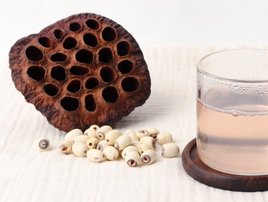 야생에서 채취를 한 연실과 연자를 하얀 바닥 위에 놓아두고 그 옆에는 투명한 컵에 연근즙을 반쯤 담아둔 것을 놓아두고 찍은 사진