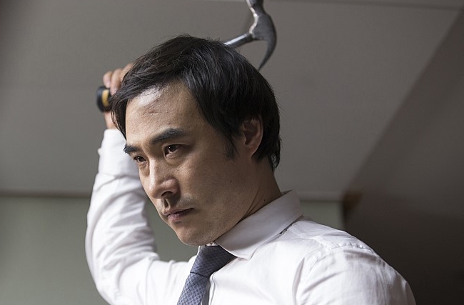 영화 오피스 김과장은 자신의 가족을 살해하기 위해 망치를 들고 있다
