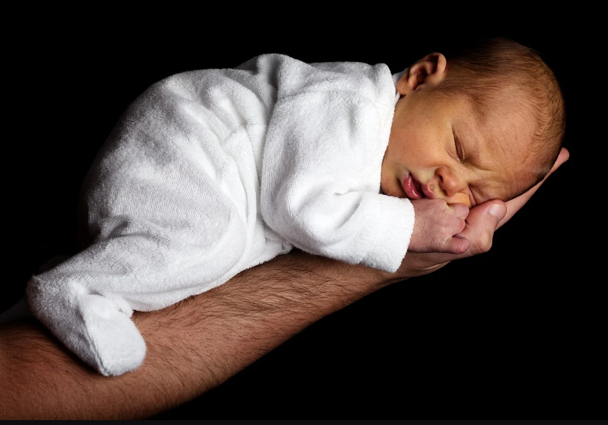 얼굴을 찡그린채 아빠 손 위에 엎드려있는 아기