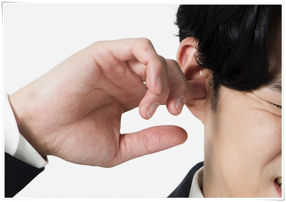 귓속에 손가락을 넣은 채 괴로운 표정을 짓고 있는 남성의 모습