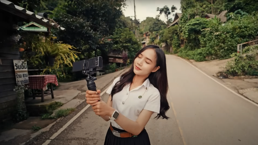 관광지에서 카메라를 들고 눈을 감고 포즈를 취하는 남어이