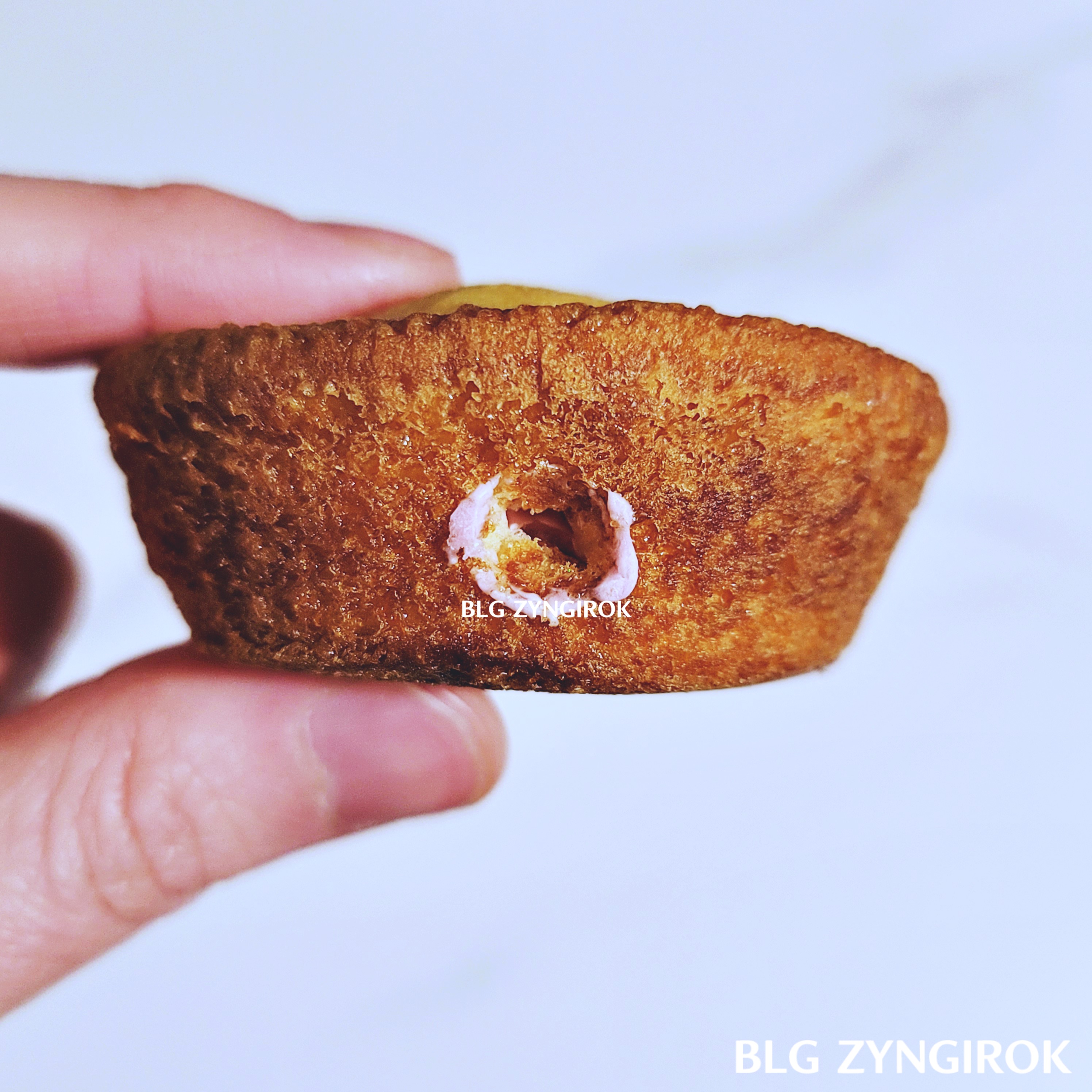 카스타드 옆면에 소스를 넣으면서 생긴 구멍의 모습이다. 구멍 주위로 스트로베리 소스가 묻어있다.