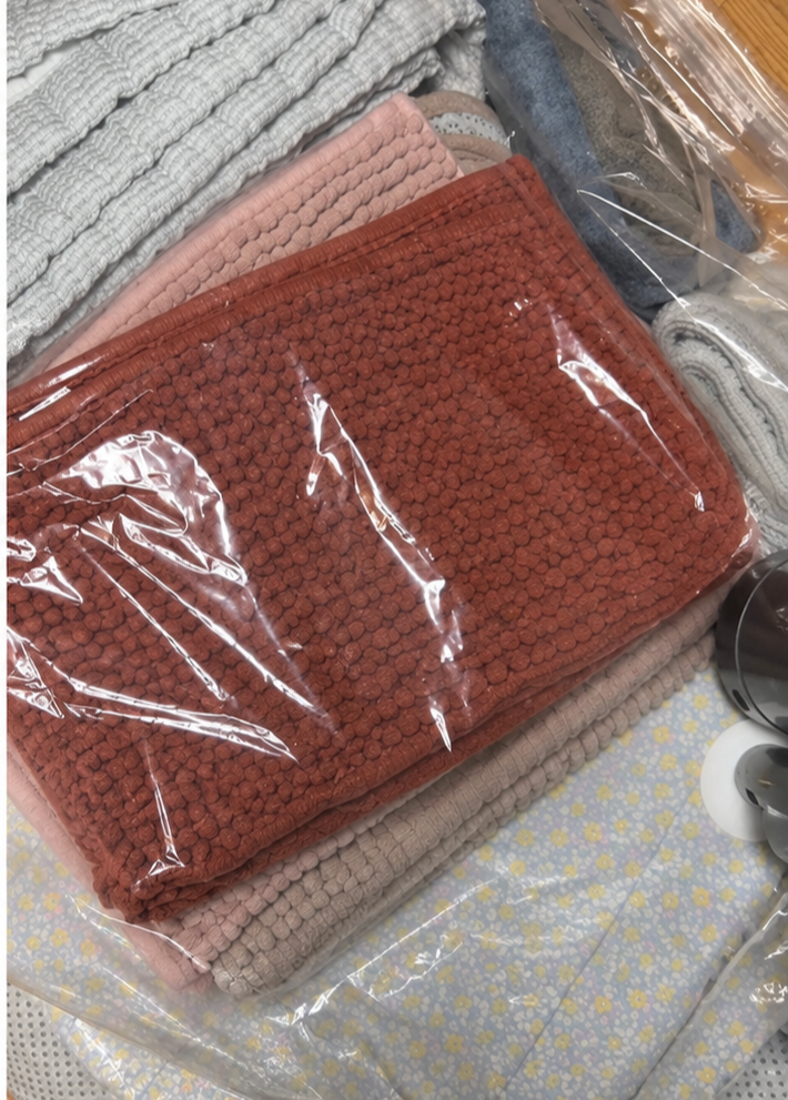 투명한 압축팩에 담겨 있는 여러 장의 이불과 러그
