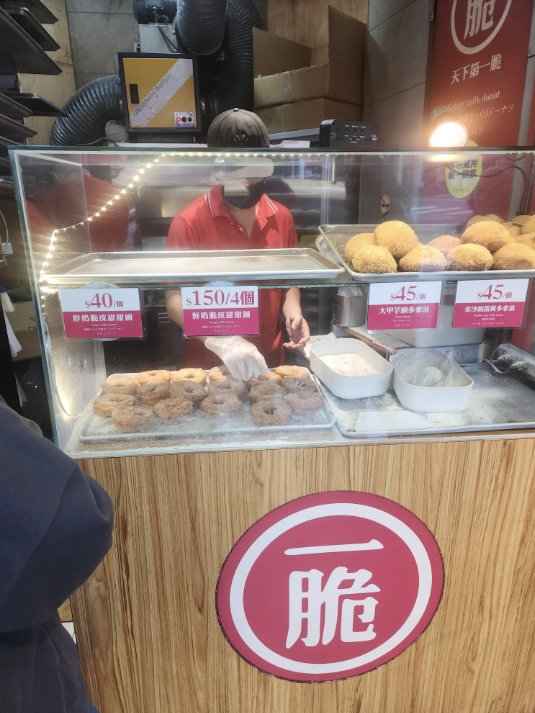 대만 크리스피 도넛 가게. 빨간 옷을 입은 직원이 도넛을 진열 중이다.