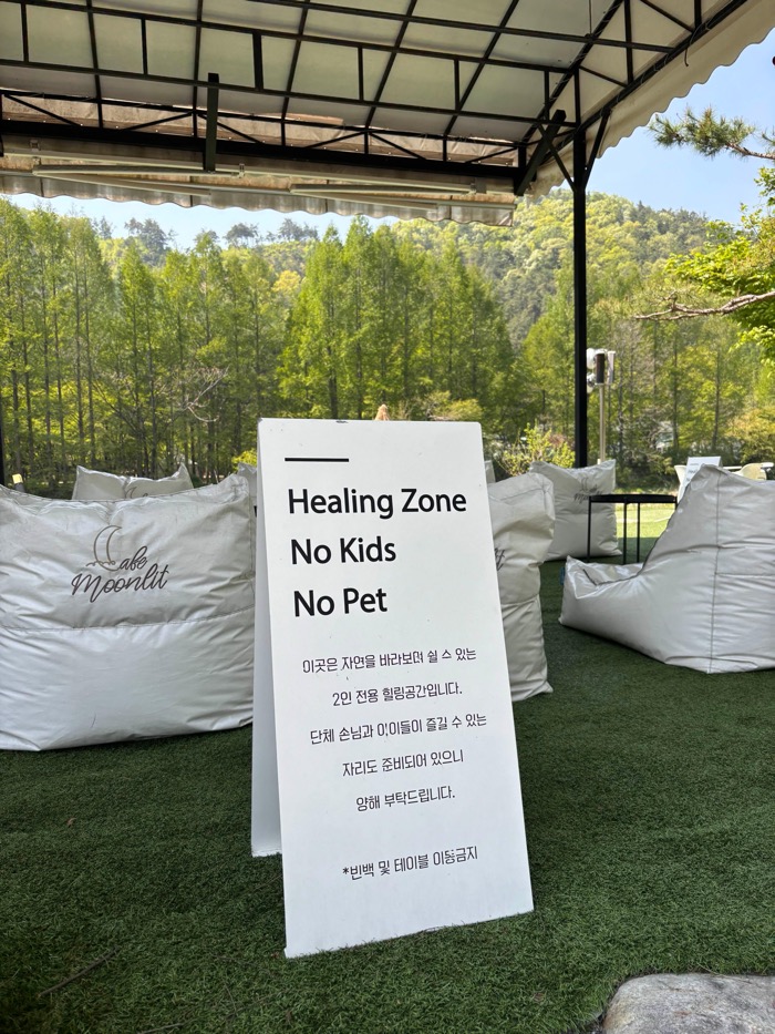 문릿 K-카페 힐링존 전경. 빈백과 ‘2인 전용, No Kids, No Pet’ 안내문.
View of the healing zone at the K-cafe Moonlit. Bean bags and a sign reading ‘Two-person only, No Kids, No Pet’.