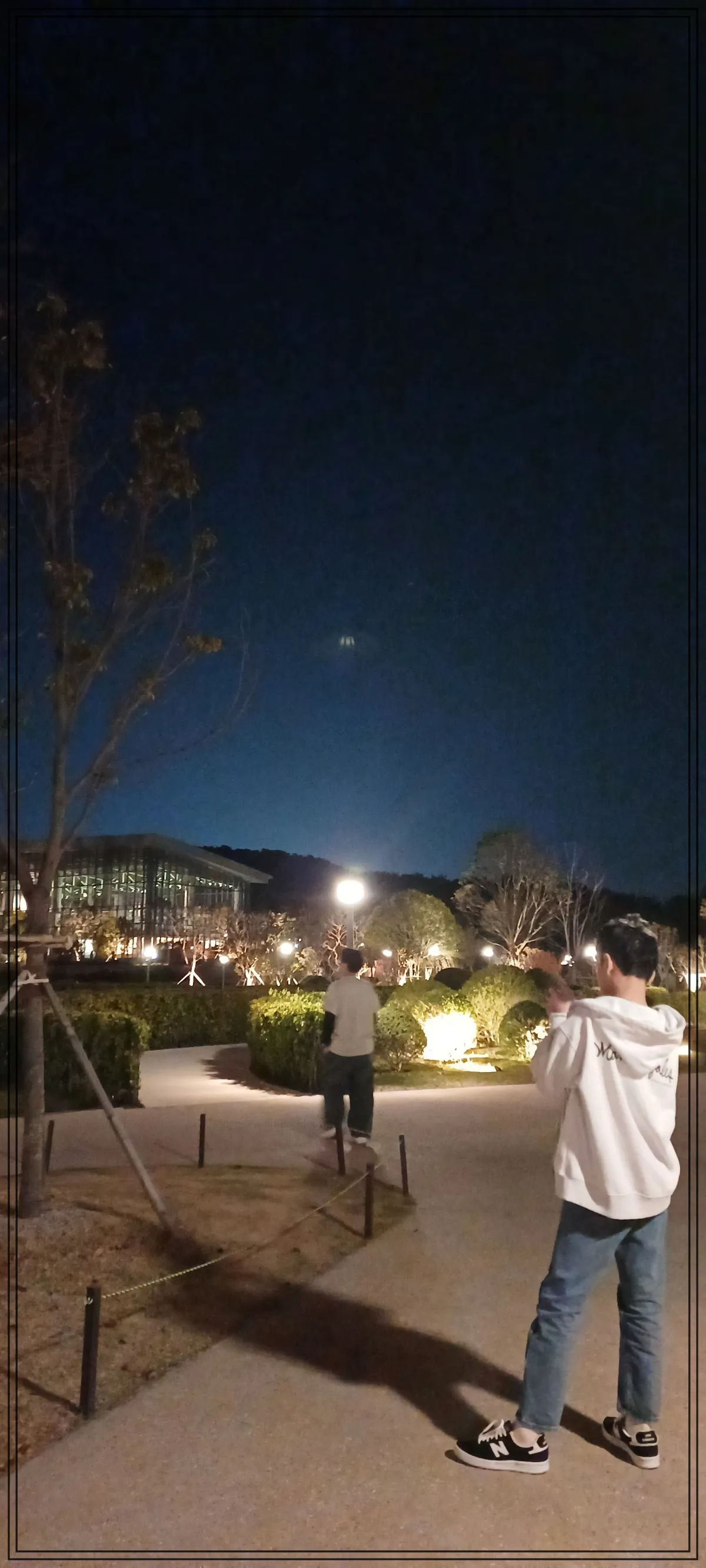 빌라쥬드-아난티-루-외부공간-산책하는-모습-밤하늘은-검고-정원같은-곳에-남자어른과-중학생-남자아이-각각-떨어져서-서-있음