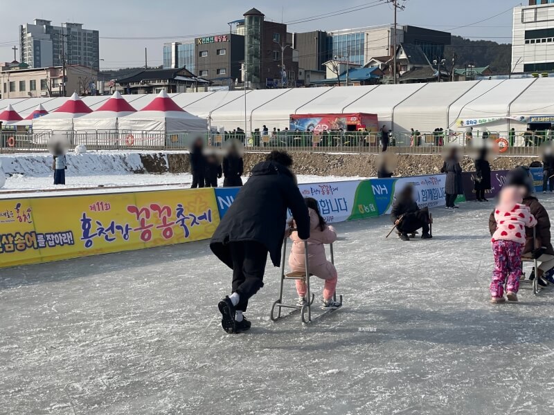무료 얼음 놀이터 에서 열심히 썰매를 미는 아빠 모습