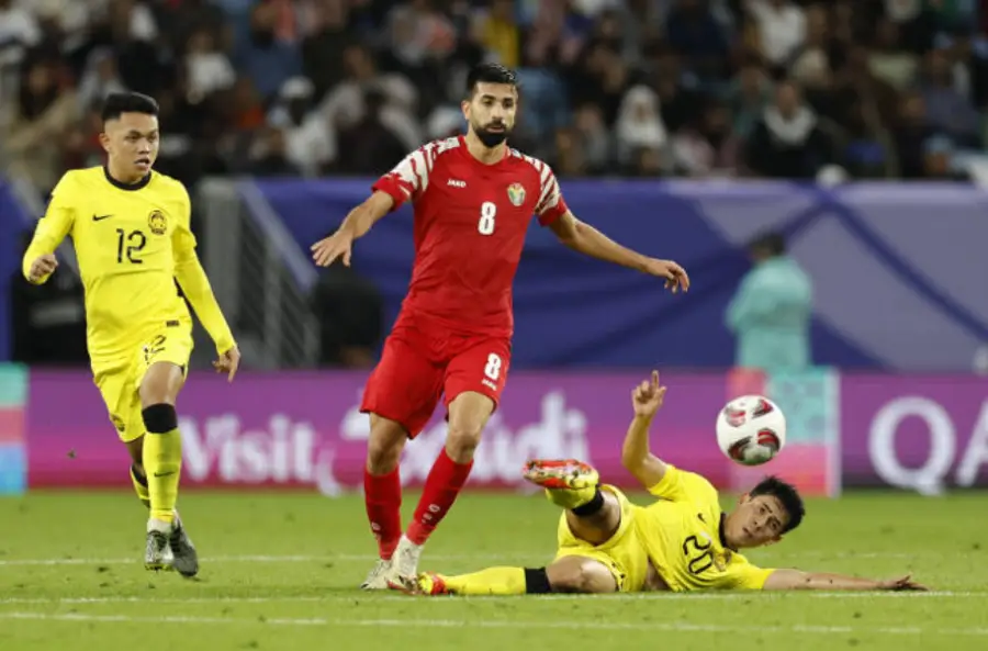 카타르 월드컵- 노란유니폼 말레이시아 선수2명이 빨간유니폼의 요르단 선수를 막고 있는 모습