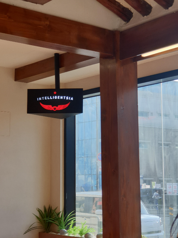 매장 입구 좌식에 있는 검은 바탕의 붉은색 날개 로고